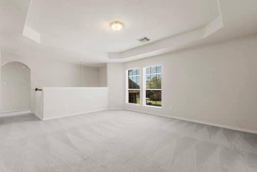 This photo shows a bright, empty room with neutral-colored walls and carpet, a window with blinds, and a ceiling light fixture. It's spacious and ready for personalization.