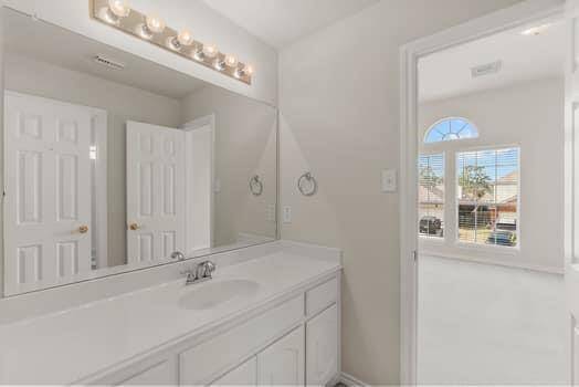 Bright, spacious room with high ceilings, neutral carpeting, and large windows featuring an arched design that allows plenty of natural light. Ideal for a bedroom or office space.