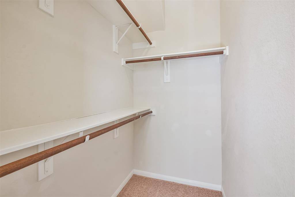 A bedroom closet featuring storage shelves and clothing racks for optimal organization.