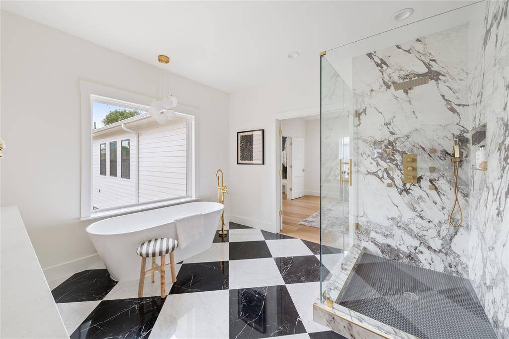 As you step through the craftsman 3-panel double doors, you'll be greeted by a luxurious bathroom featuring separate his and hers vanities and a tub overlooking your front yard.