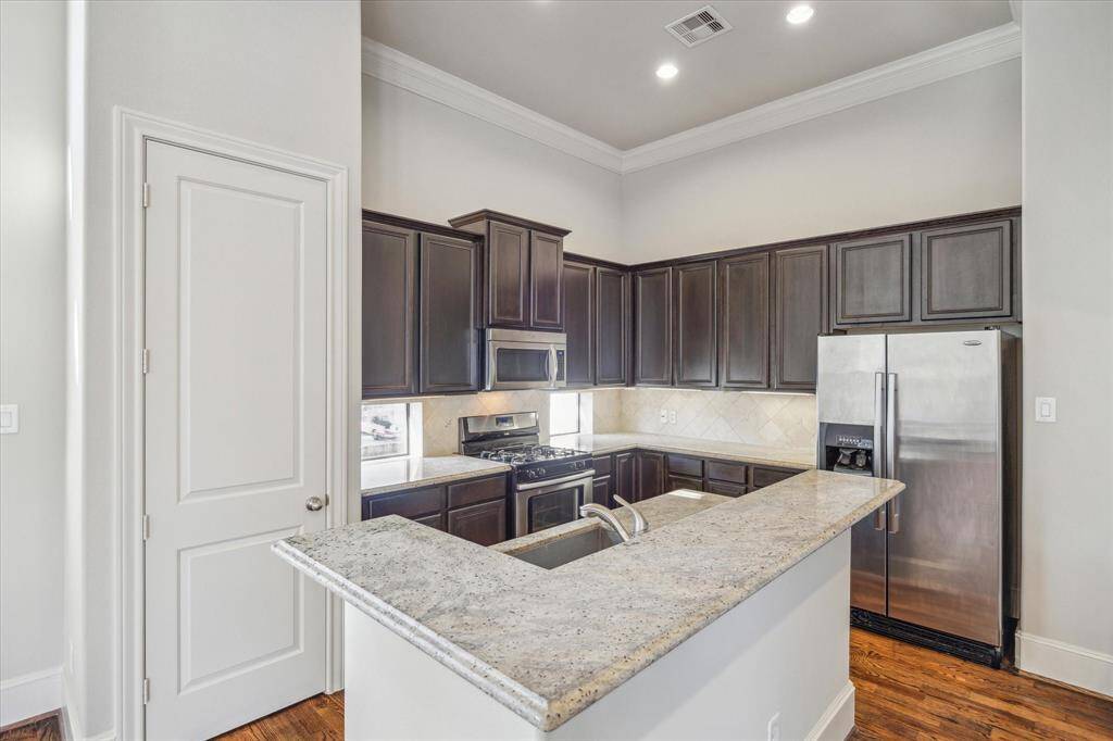 Modern kitchen with dark wood cabinets, stainless steel appliances, and a granite countertop. Bright and spacious with an open layout.