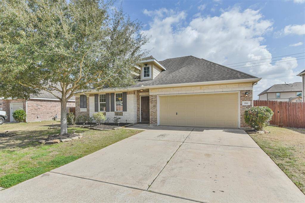 BBrick and stone veneer complemented by dormers, featuring a spacious double-wide driveway.