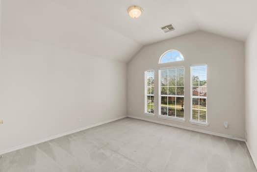 This photo shows a bright, third bedroom with nuetral painted walls and carpet. It features a sloped ceiling and a simple ceiling light and great closet space