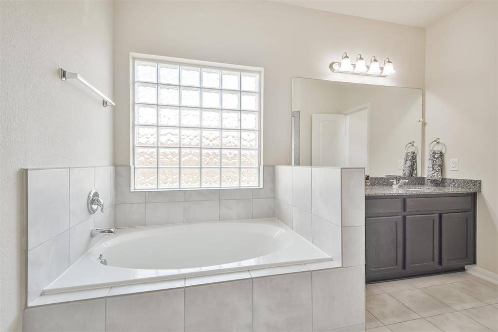 A luxurious soaker tub elegantly framed with ceramic tile and enhanced by soft block lighting.