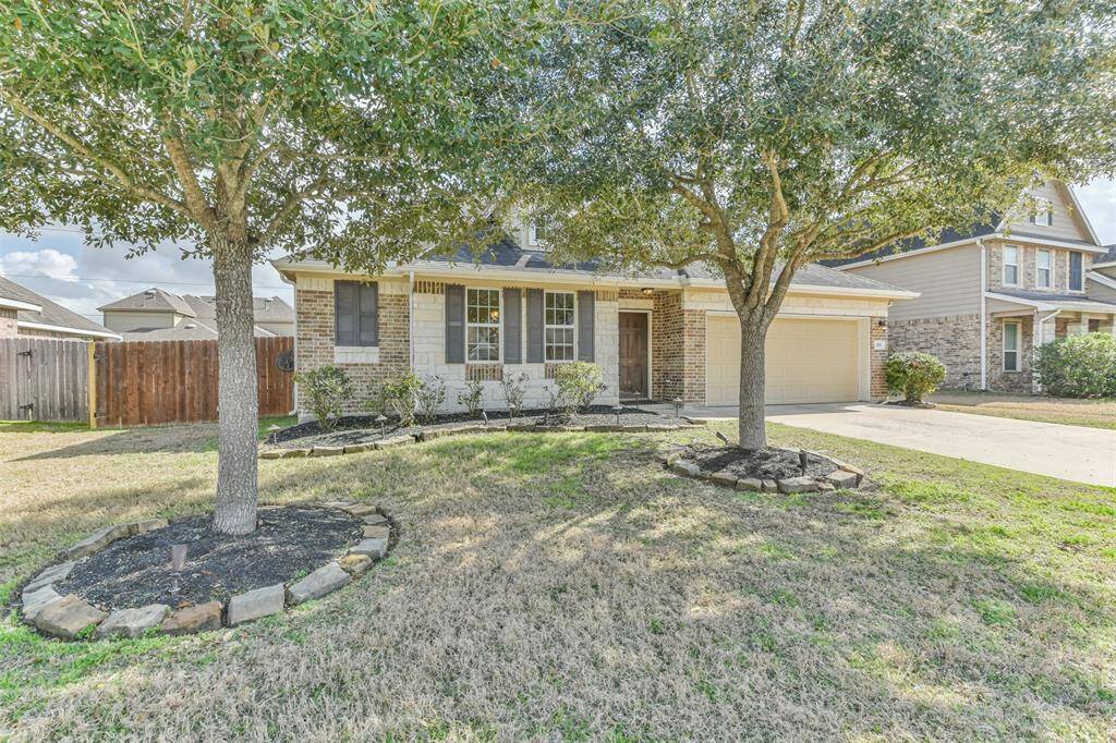 Majestic oak trees complemented by elegant stone accents adorn the landscape, seamlessly blending with the front shrubbery.