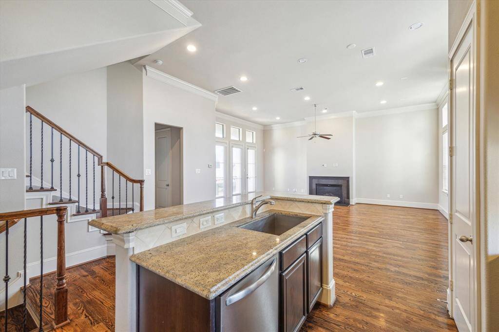 This spacious open-concept living area features hardwood floors, a modern kitchen with granite countertops, and a cozy fireplace. High ceilings and large windows provide ample natural light, creating a warm and inviting atmosphere.