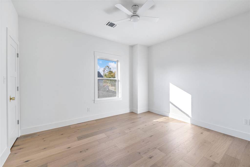 One of three secondary bedrooms. Secondary bedrooms boast stunning hardwoods, natural light from new windows, and ceiling fans.