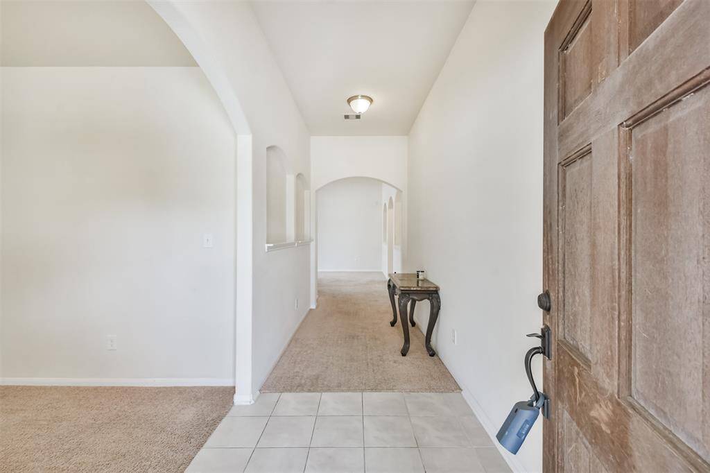 Ceramic tile flooring in the entryway paired with elegant arched doorways.