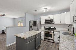 View of the open island kitchen. Laminate floors, granite cointers.