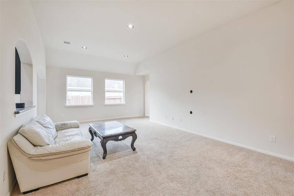 A spacious family room featuring tall ceilings, recessed lighting, and a convenient service window connecting to the kitchen.
