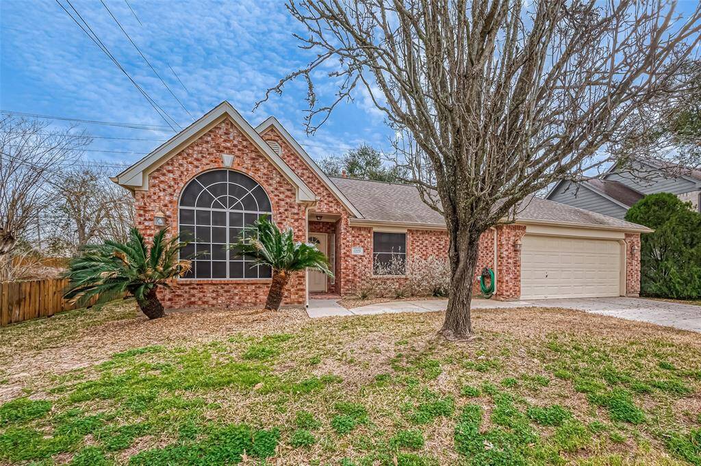 The home's warm brick exterior pairs beautifully with the mature tree on the front lawn, creating an eye-catching streetscape. Dark green plants adorn the facade, adding contrast to the brickwork and enhancing the curb appeal.