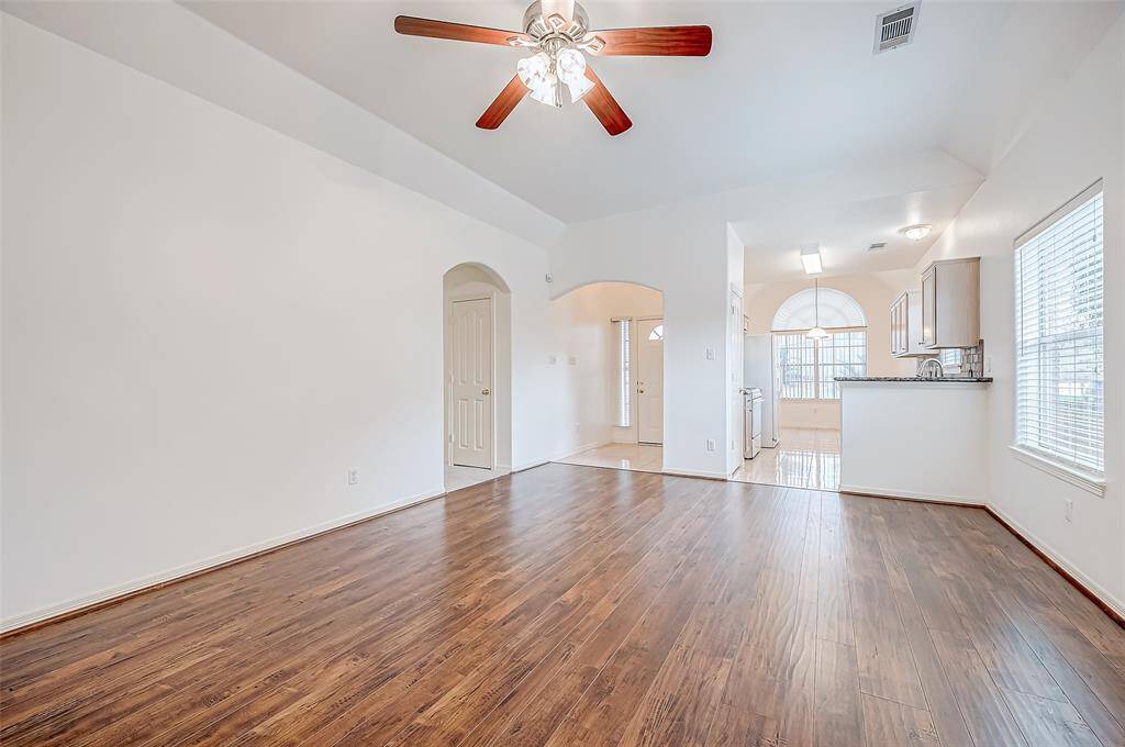 This expansive living room offers versatility, with clean archways leading to the surrounding spaces. With its open connection to the kitchen, this room is ideal for both everyday comfort and entertaining.