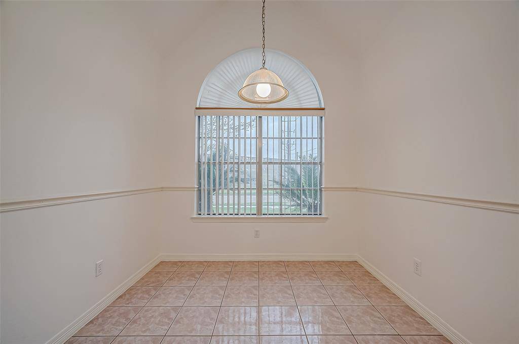 Nestled beneath a sloping ceiling, this breakfast area feels like a private alcove. The oversized arched window brings in plenty of natural light while offering a picturesque view of the outdoors. A pendant light adds a decorative touch, making the space feel complete.