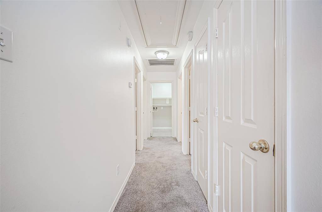 A softly carpeted hallway leads to the bedroom areas, with crisp white walls and doors brightening the space. The neutral tones keep the area feeling fresh and inviting.