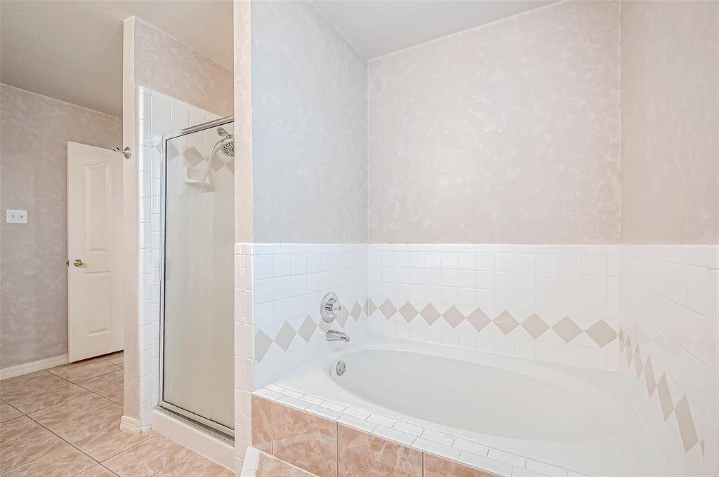 The enclosed shower and deep garden tub offer flexibility, whether for a quick refresh or a long soak. A built-in linen closet ensures effortless organization.