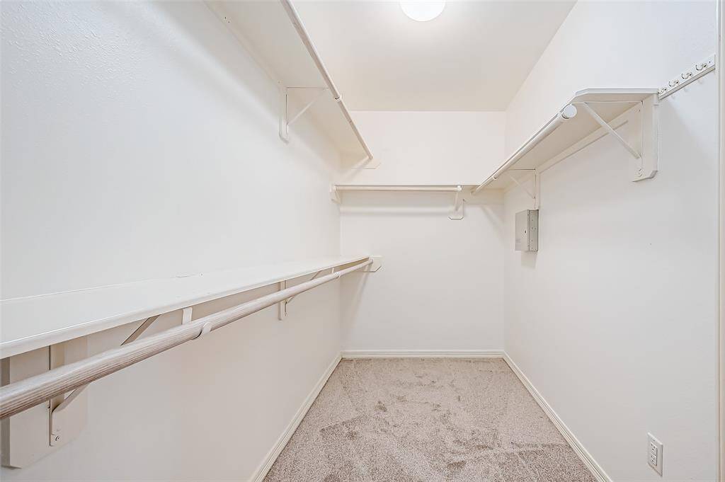 This spacious closet features built-in racks for optimized organization. Carpeted floors add comfort underfoot, making it easy to arrange belongings.