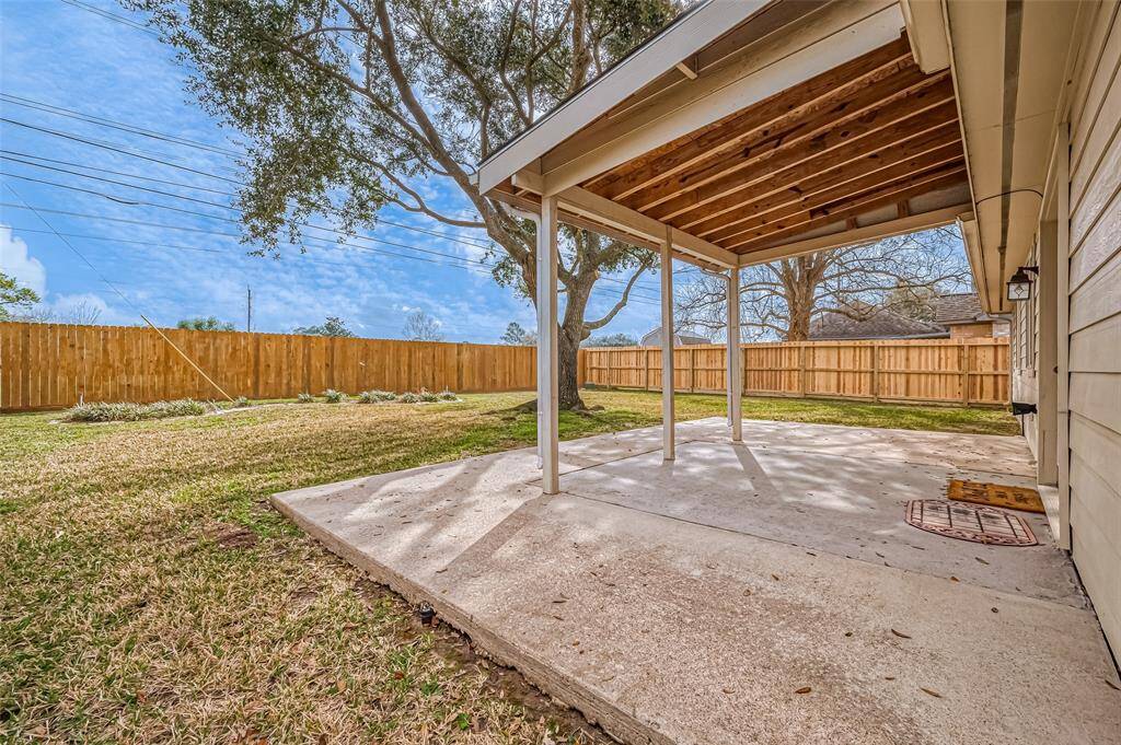 Extending from the home, this partially covered patio offers a versatile outdoor space. The concrete slab provides a solid foundation, while the expansive grassy area beyond allows for recreation or landscaping creativity.