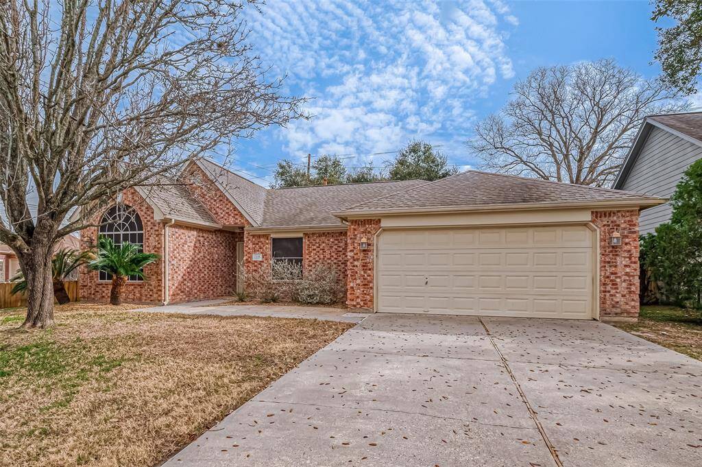 The home's facade balances classic charm with practical design, featuring a two-car garage and a well-maintained driveway.