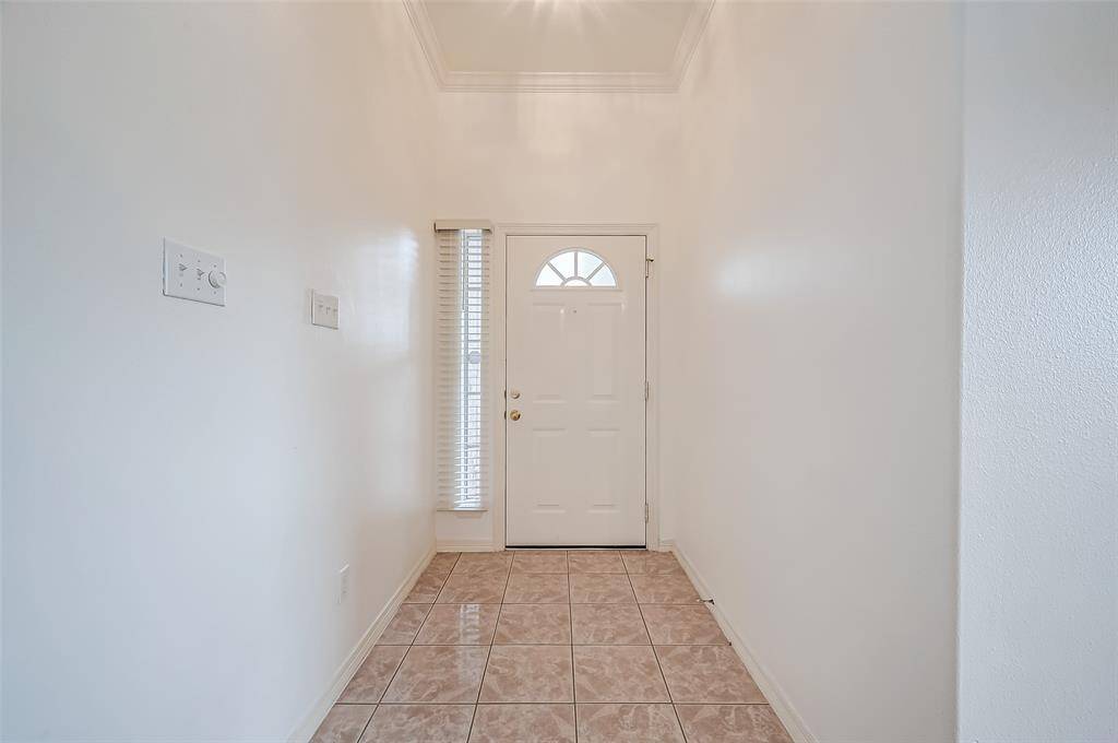 Stepping inside, the well-lit entryway opens up to a grand view of the main living area through a wide, graceful archway. The neutral walls enhance the brightness.