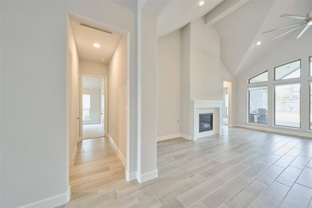 As you approach the Living area from the grand entry, you're met with a beautiful wall of windows and fireplace ahead.  Hallway to some of the secondary bedrooms to the left.  Schedule your tour today at 136 Hushed Nightfall, The Woodlands Hills, Willis, Tx