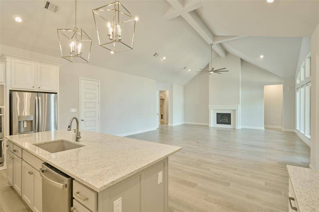 True open-concept design incorporates dream kitchen, dining space and beautiful well-lit living area in front of the fireplace. View from the fireplace wall at 136 Hushed Nightfall.