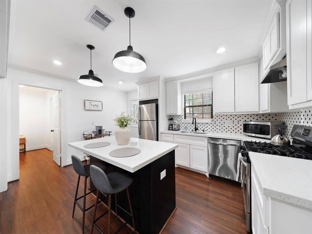 The kitchen is beautifully updated with modern fixtures, stainless steel appliances, Quartz countertops and an oversized kitchen island with pendant lights.
