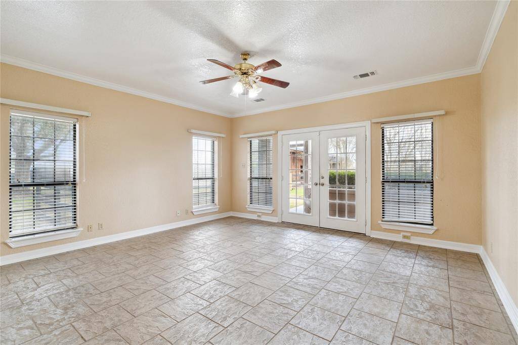 This bright, spacious room features large windows with blinds, a ceiling fan, and neutral tile flooring. Tons of natural light.