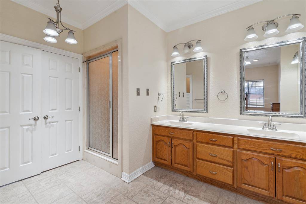 Walk-in shower with a frosted glass door and ample lighting. The space is bright, with neutral tiles and a window providing natural light.