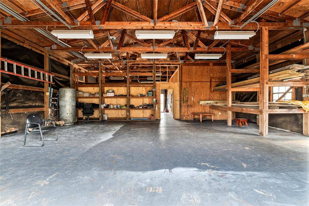 Exposed wooden beams, ample shelving for storage, and a large open area perfect for workshops or parking. Ideal for DIY projects or extra storage space.