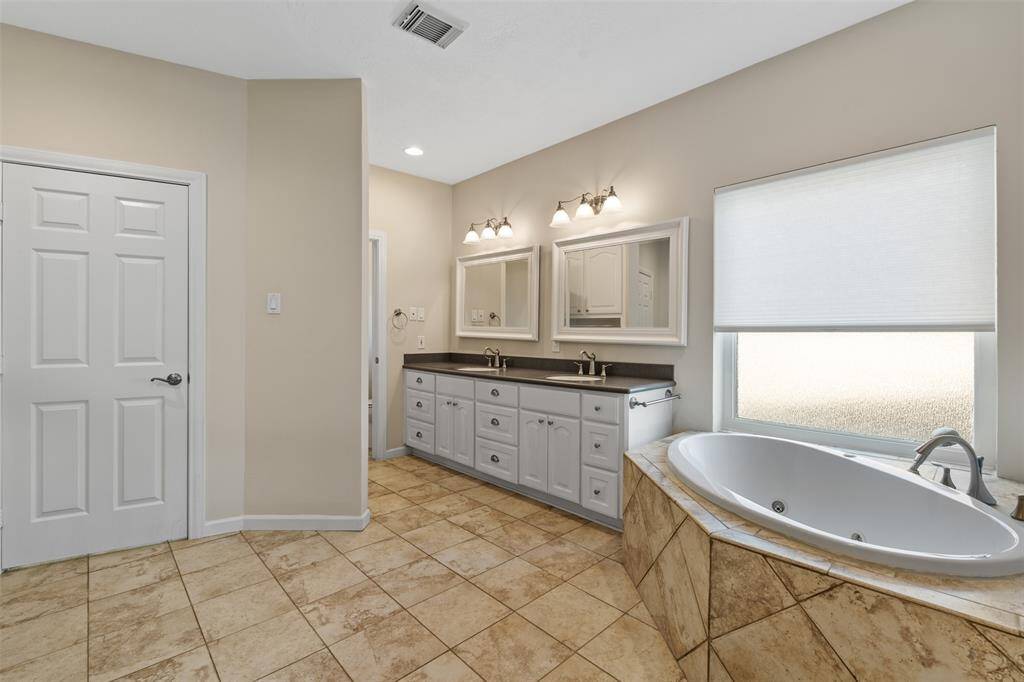 The large primary bathroom offers a spa-like experience, featuring a soaker tub, a separate walk-in shower, dual vanities, and ample storage. It’s the perfect space to relax and unwind after a long day