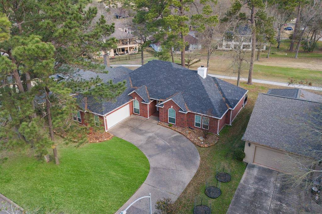 The aerial view highlights the home's prime location within the prestigious Walden on Lake Conroe community, showcasing the spacious golf course lot, beautiful outdoor living spaces, and the surrounding scenic landscape.