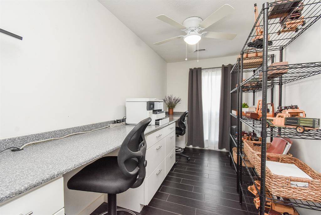 Home office has built in counter with 2 desk spaces, built in drawers and storage shelving