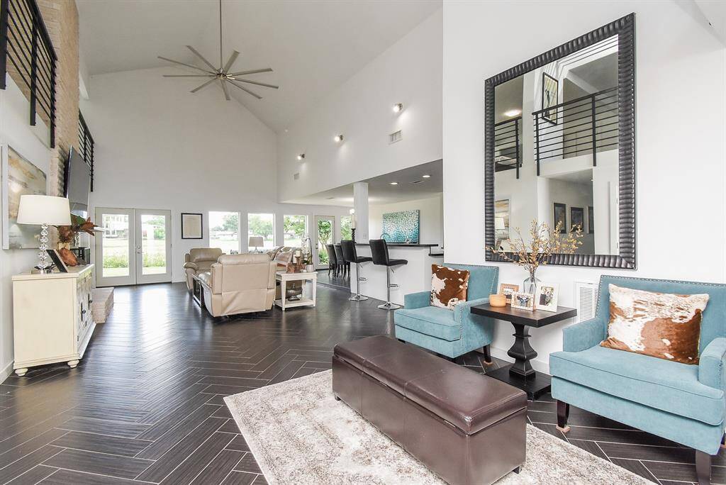Incredible open feel in the Living room with porcelain wood grain flooring in herringbone pattern throughout. Yes that is a 96" ceiling fan and wall of windows overlooking golf course and water view