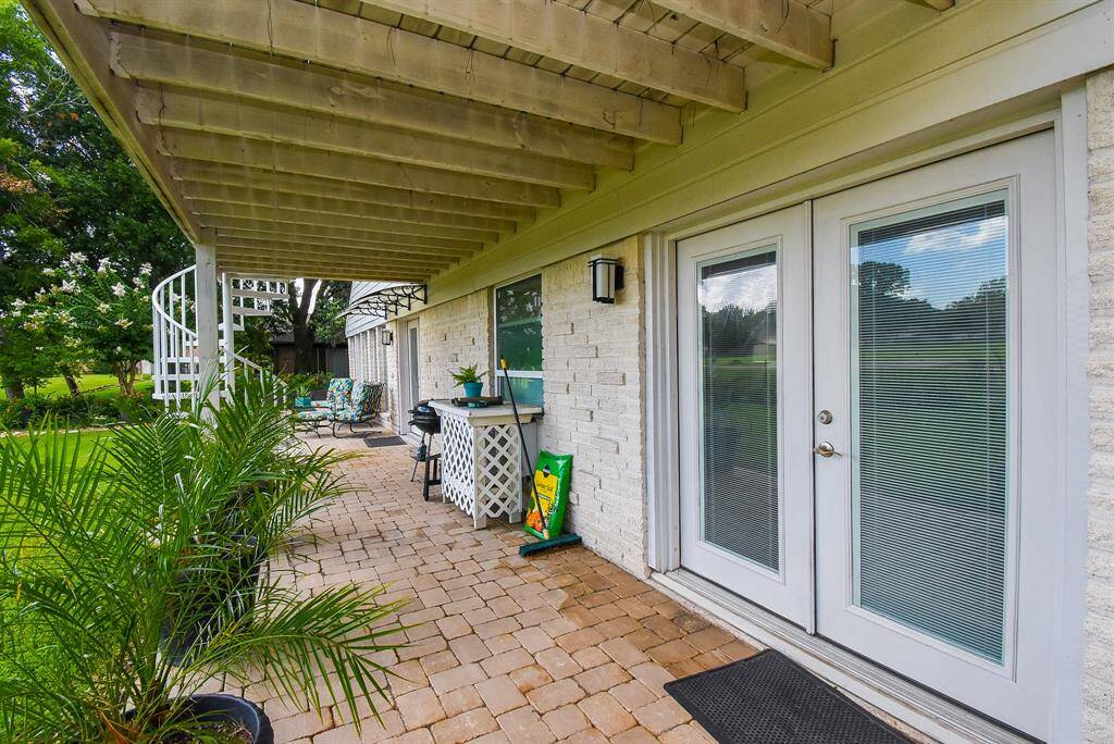 Balcony provides a covered patio with clay tile pavers and spiral staircase. Doors are into Primary bedroom.See how a hot tub would work perfectly out here?