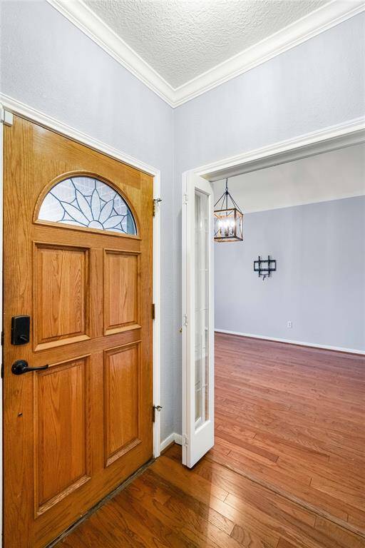 Foyer entrance with hardwood floors, molding and textured ceiling