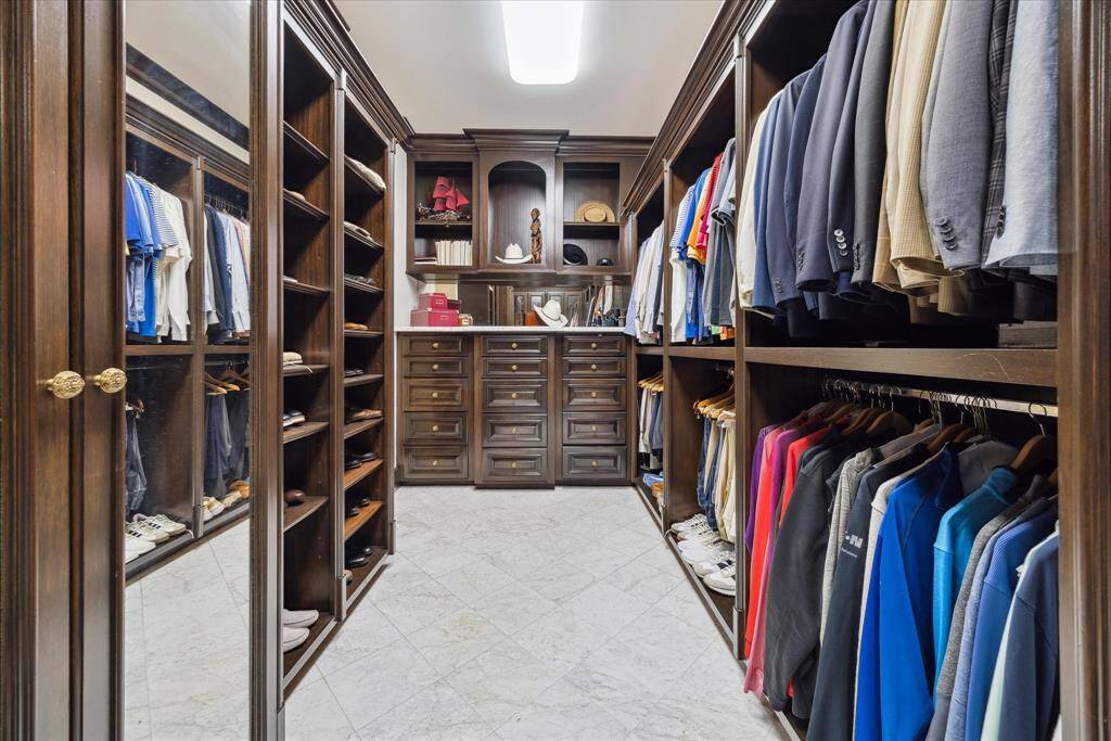The second closet in the primary is handsomely outfitted with dark stained wood built-ins.