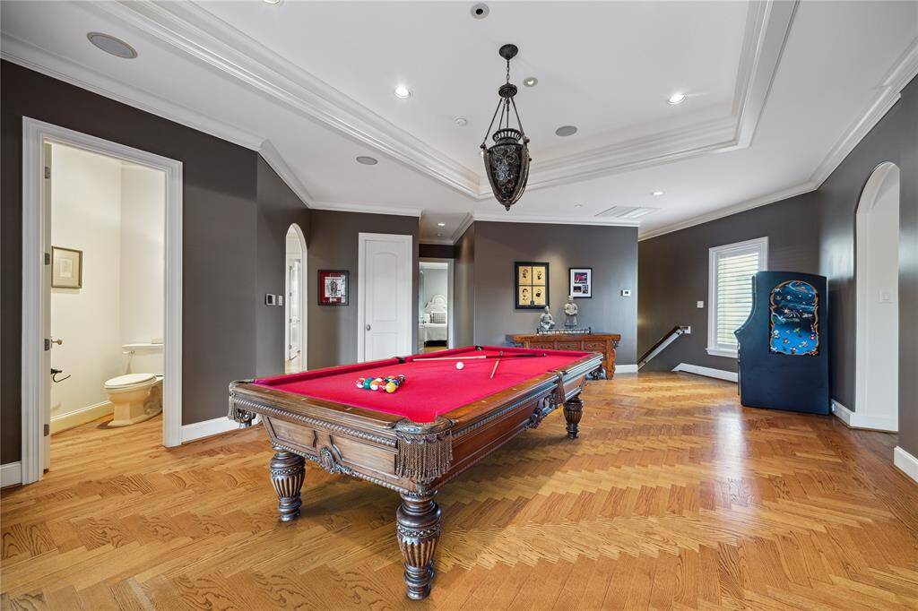 The billiard room is grand with the tray ceiling and Tiffany-style pendant.  Herringbone wood flooring adds to its appeal.