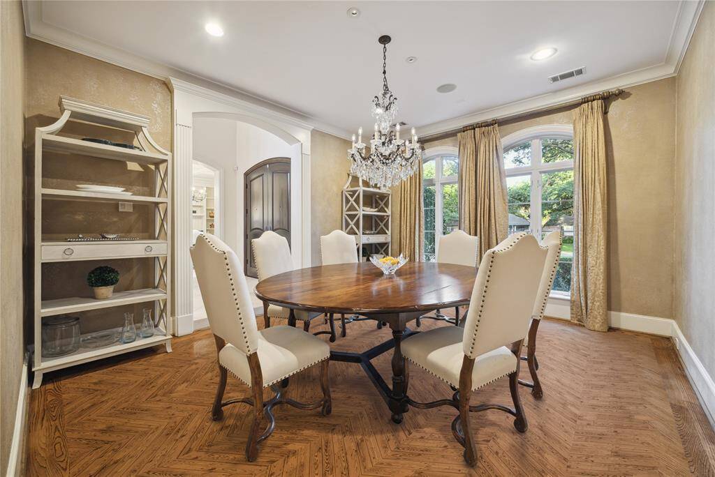 The elegant dining room is punctuated by a Schonbek crystal chandelier, custom Segreto finished walls, and herringbone wood flooring.