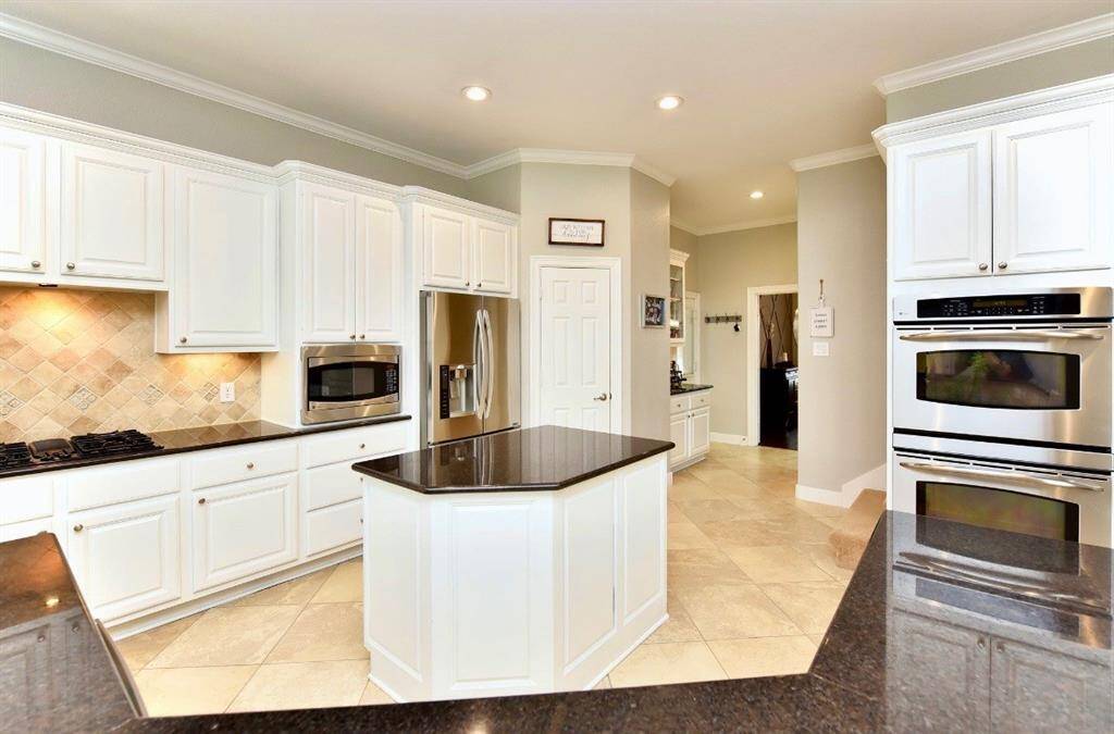 Stainless steel appliances, sleek granite counters and ample countertop space surround the island of this spacious kitchen.