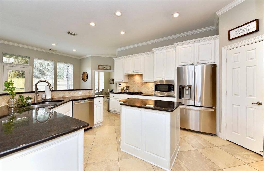 Stainless steel appliances, sleek granite counters and ample countertop space surround the island of this spacious kitchen.
