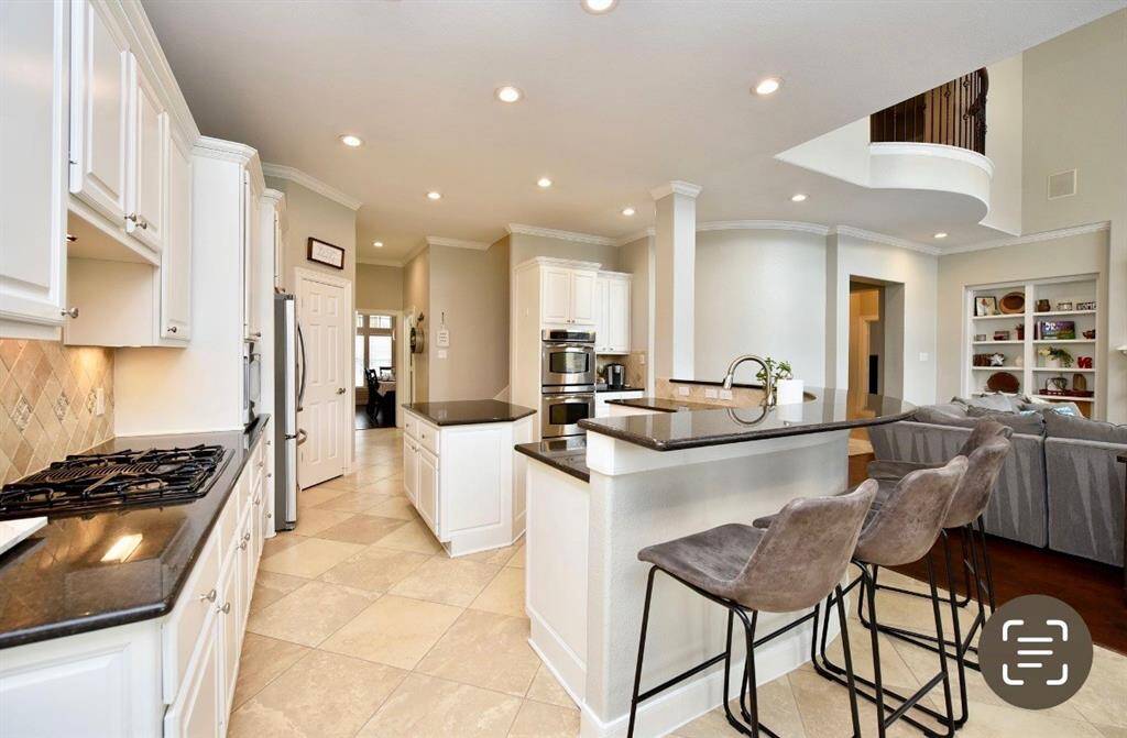 Stainless steel appliances, sleek granite counters and ample countertop space surround the island of this spacious kitchen.