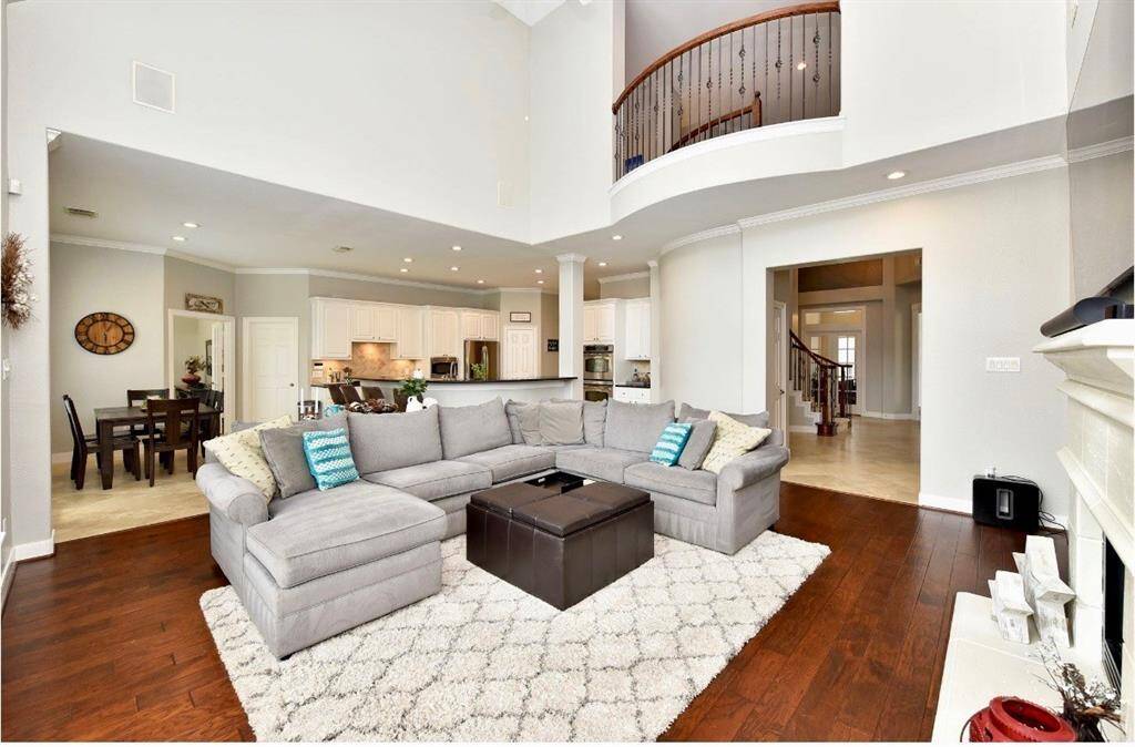 The living room features a bright atmospheric feel with a luxurious hardwood floors, soaring ceilings and inviting views of the gorgeous pool.