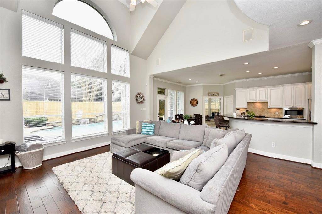 The living room features a bright atmospheric feel with a luxurious hardwood floors, soaring ceilings and inviting views of the gorgeous pool.