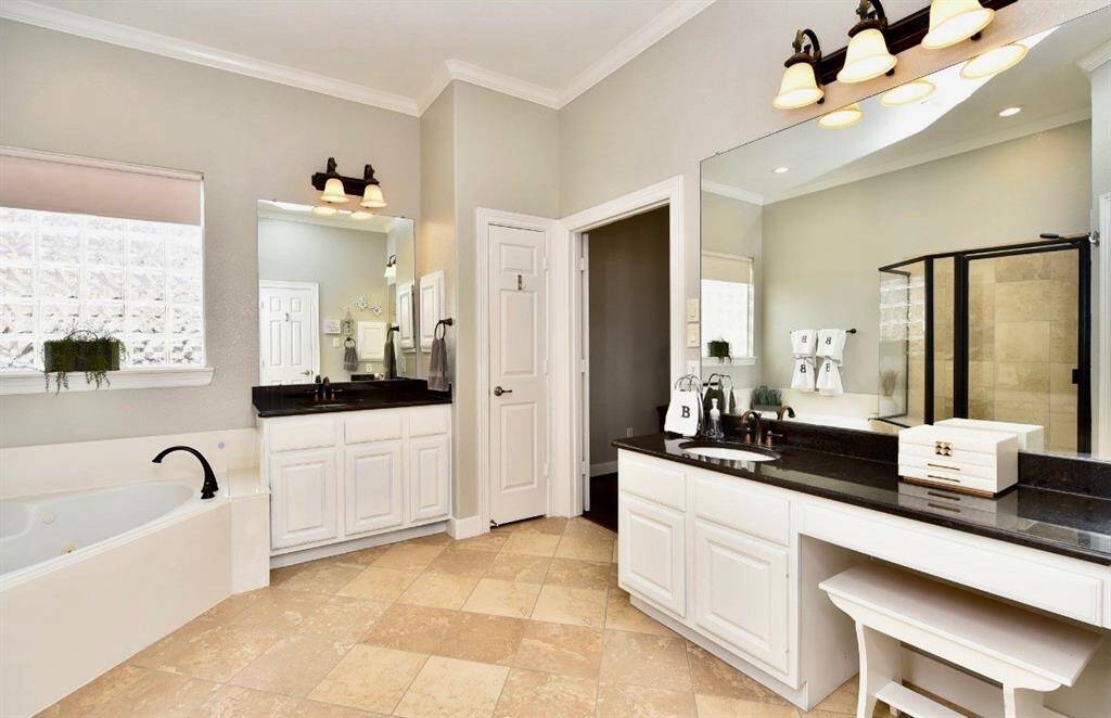 The primary bath is spacious featuring a large garden tub, his and her closets and vanities, dark bronze framed mirrors and shower to match.