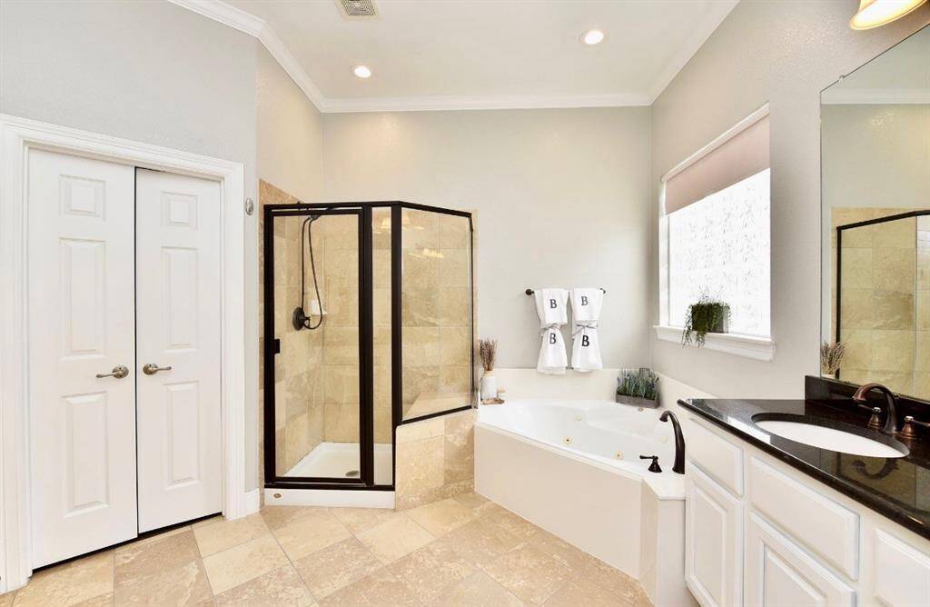 The primary bath is spacious featuring a large garden tub, large walk-in his and her closets and vanities, dark bronze framed mirrors and shower to match.