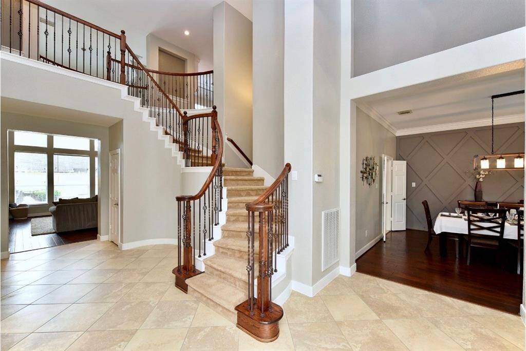 The covered front entry is inviting and optens to a bright foyer with soaring ceilings near the primary office and formal dining room.