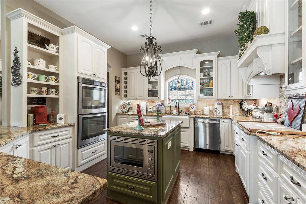 The central island with a built-in microwave adds functionality, while the large window provides ample natural light. A charming chandelier enhances the room's sophisticated design.