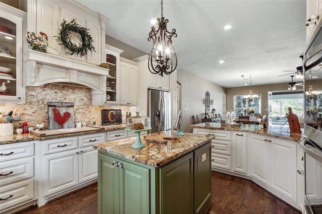 Gorgeous custom vent hood, double ovens and ample cabinets for your storage are featured. The open layout flows into a dining area with plenty of natural light, highlighted by stylish pendant lighting.