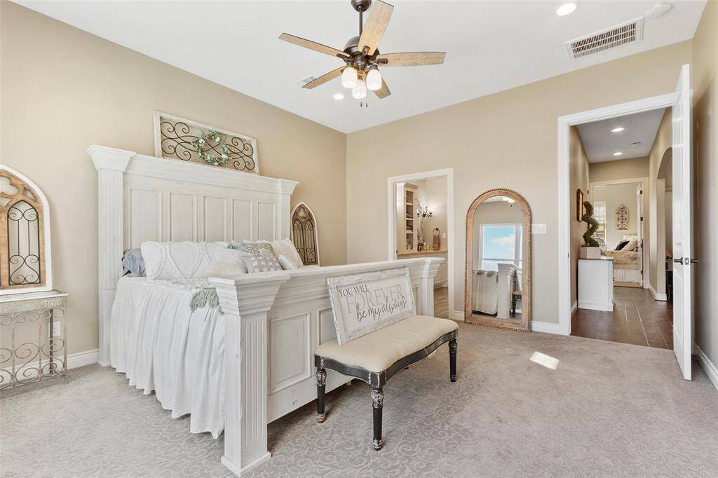 This spacious bedroom features a light, neutral color palette and ample natural light. The room connects to an en-suite bathroom.