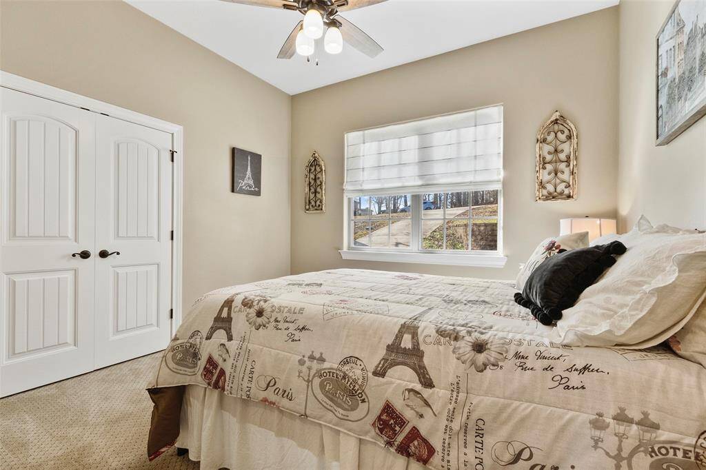 This cozy secondary bedroom features neutral tones, a large window, ceiling fan, and carpet. It has double doors for great closet access and storage space.